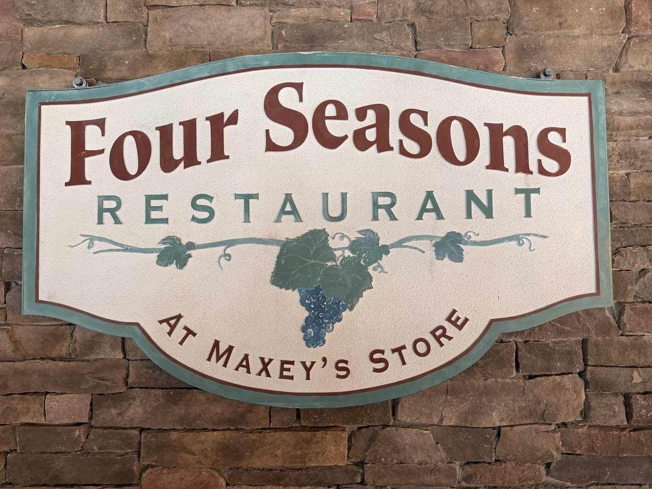 Four Seasons Restaurant logo on a stone wall, with the inscription 'at Maxey's Store'